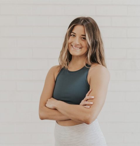 Smiling woman in athletic wear, arms crossed.