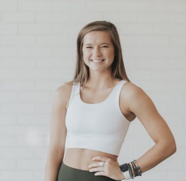 Smiling woman in athletic wear, white background.