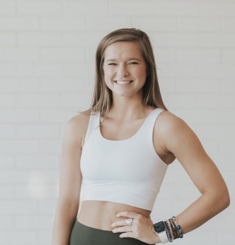 Smiling woman in athletic wear, white background.