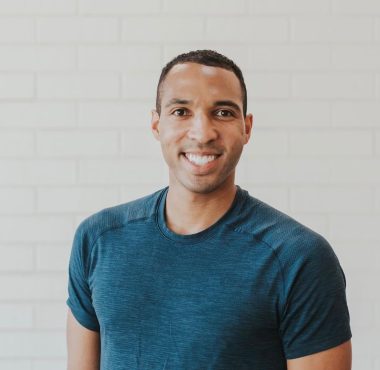 Smiling man in blue shirt, white background.