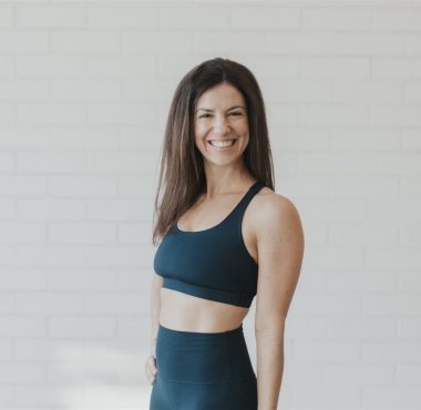 Woman smiling in workout attire, white background.