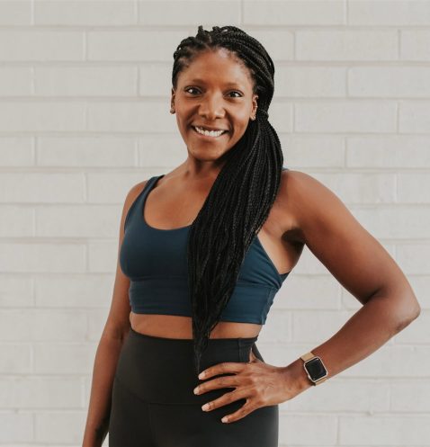 Smiling woman in workout attire, posing confidently.