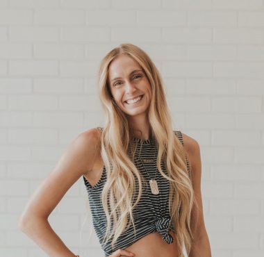 Woman smiling in front of white brick wall.