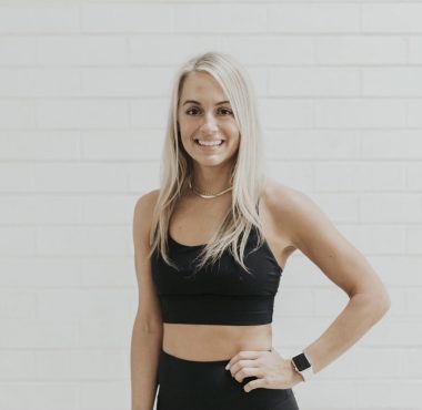 Woman in black sportswear smiling confidently.