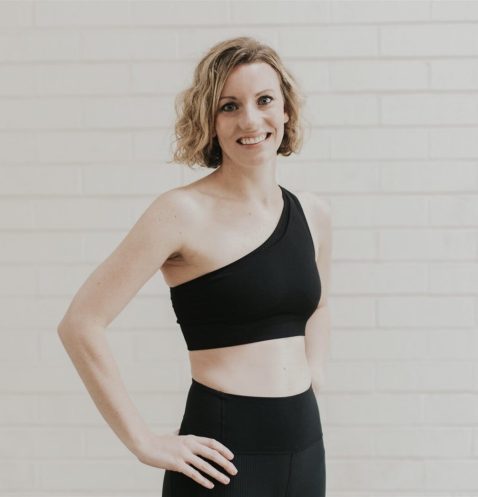 Woman in black workout outfit smiling.