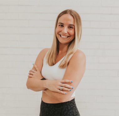 Smiling woman with crossed arms, white background.