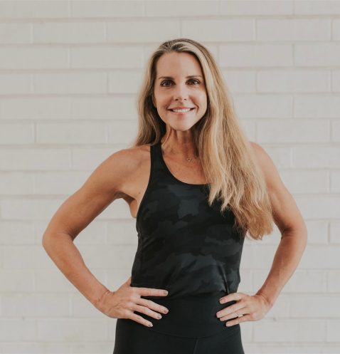 Woman in black tank top smiling confidently.