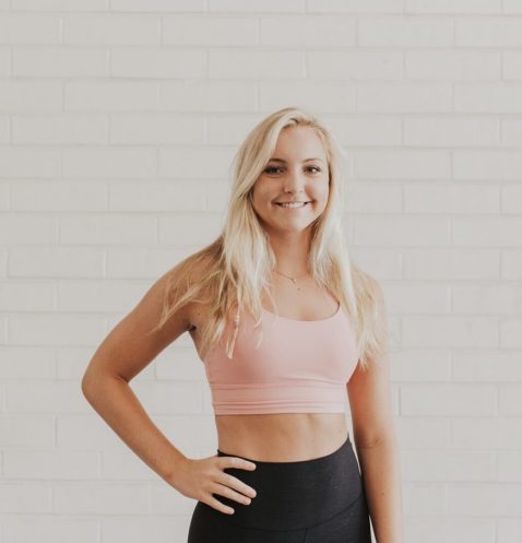 Woman in pink sportswear against brick wall.