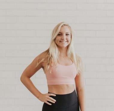 Smiling woman in activewear against white wall.