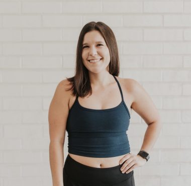 Smiling woman in workout attire, white background.