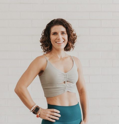 Smiling woman in workout attire, white background.