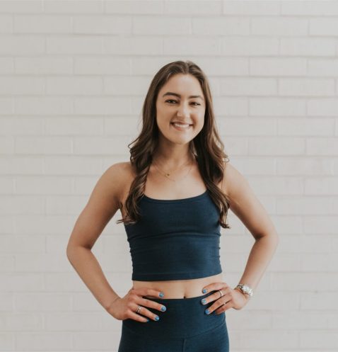Smiling woman in athletic wear against wall.