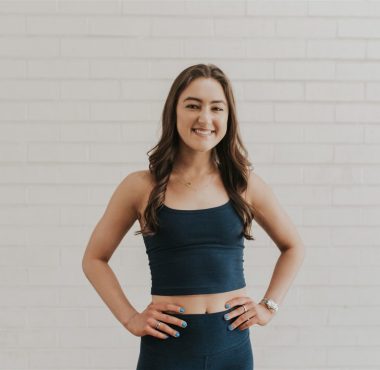 Smiling woman in workout attire against bricks.