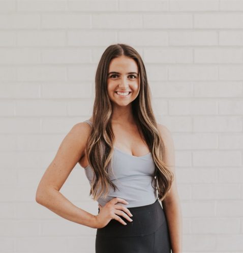 Smiling woman posing against white brick wall.
