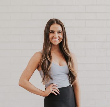 Smiling woman against a white brick wall.