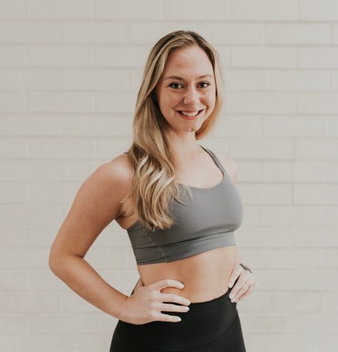 Smiling woman in athletic wear poses confidently.