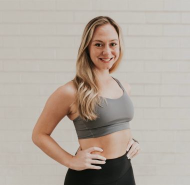 Smiling woman in workout attire, white background.