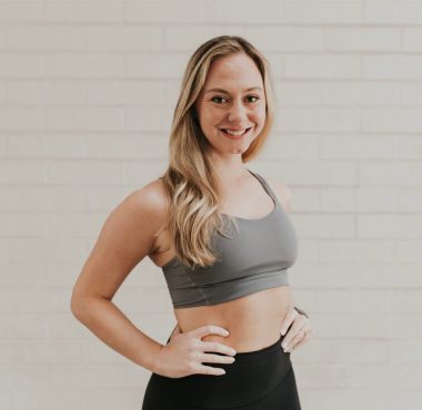 Smiling woman in workout attire, white background.