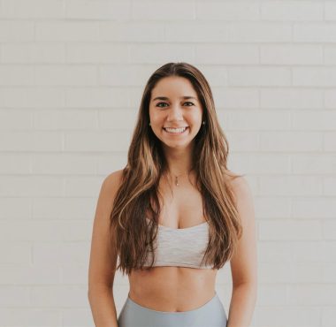 Smiling woman in athletic wear, white background.
