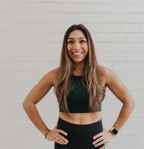Smiling woman in workout attire against wall.