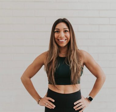 Smiling woman in athletic wear, white background.