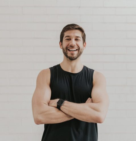 Smiling man in black sleeveless shirt.