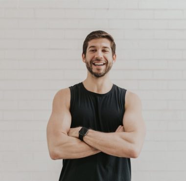 Man smiling with crossed arms, wearing black.
