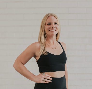 Woman in black workout attire smiling.