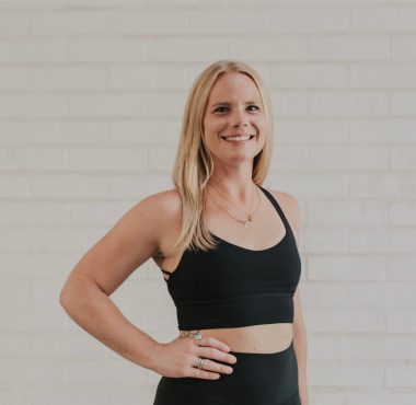 Woman in black workout attire smiling.