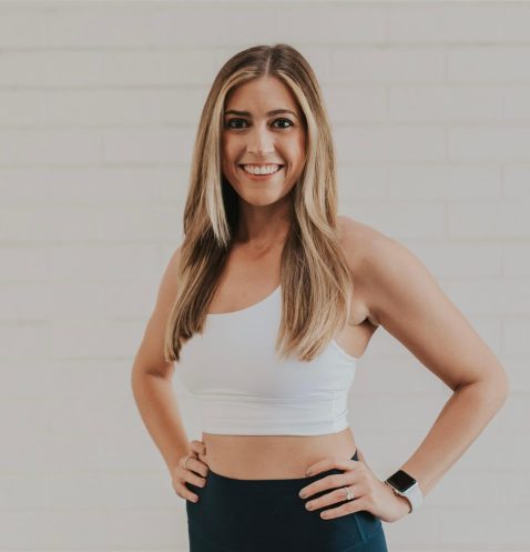 Smiling woman in athletic wear against wall.
