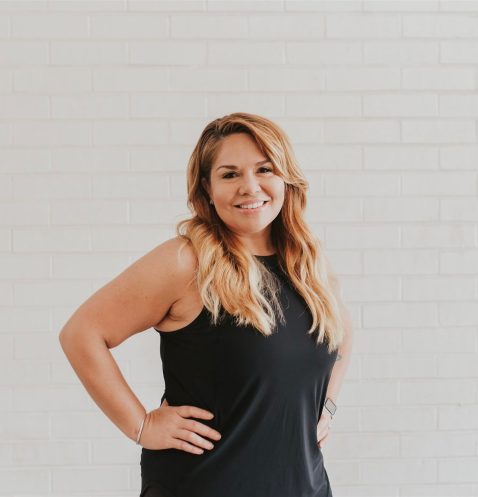 Smiling woman in black dress, white background.