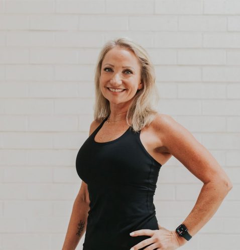 Smiling woman in black top, white background.