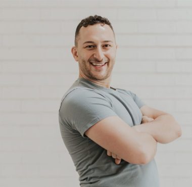 Smiling man standing with crossed arms.