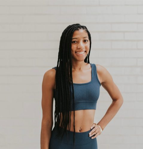 Woman in sportswear smiling against brick wall.