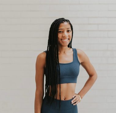 Smiling woman in athletic wear, braided hair.