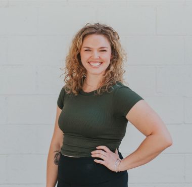 Smiling woman in green shirt posing outdoors.