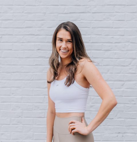 A woman standing in front of a brick wall.