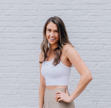 A woman standing in front of a brick wall.