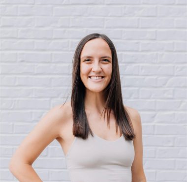 Smiling woman in sportswear against brick wall.