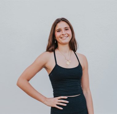 A woman in black top standing next to wall.