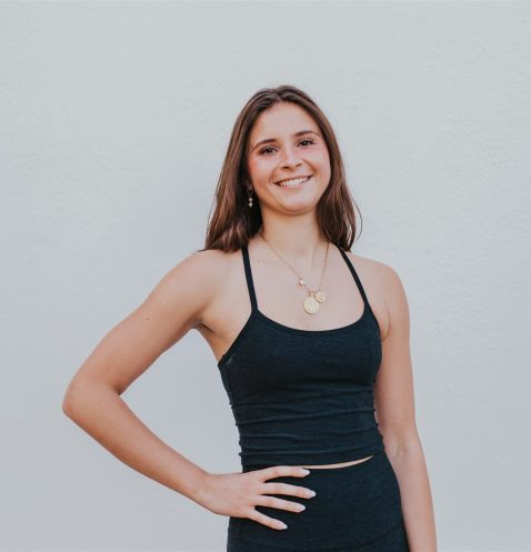 A woman in black top standing next to wall.