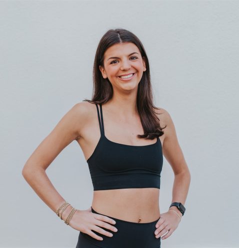 A woman in black top standing with hands on hips.