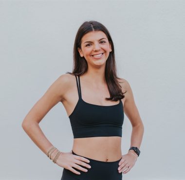 A woman in black top standing with hands on hips.