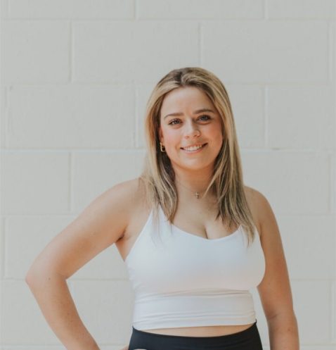 Smiling woman in workout attire against wall.