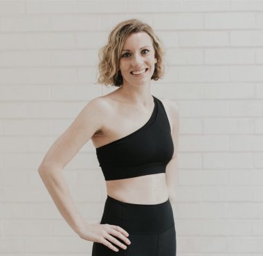 Woman in black athletic wear, smiling confidently.