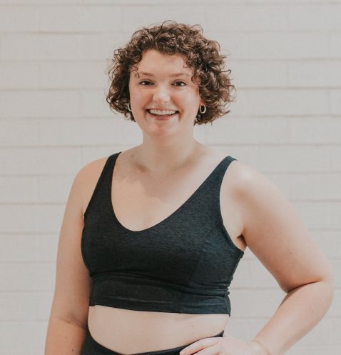 A woman in black sports bra standing next to wall.