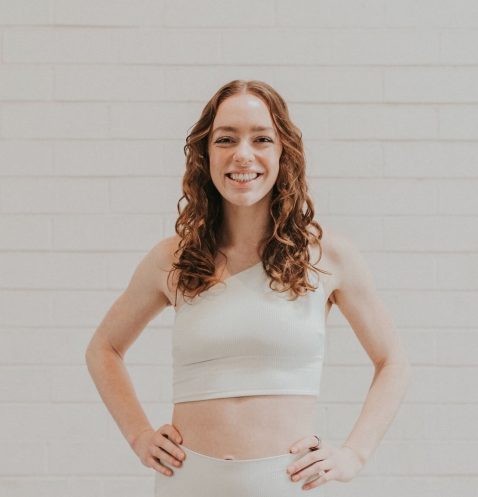 A woman standing in front of a white wall.