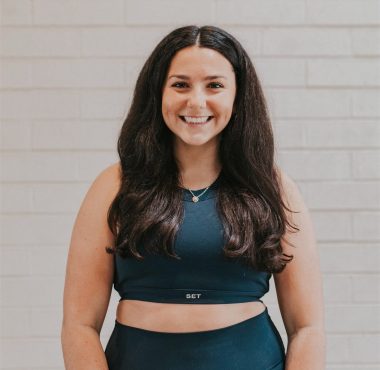 A woman standing in front of a brick wall.