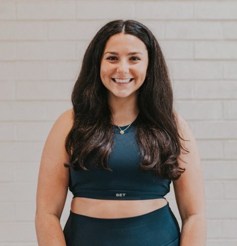 A woman standing in front of a brick wall.