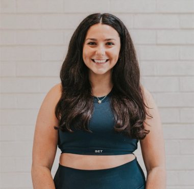 A woman standing in front of a brick wall.